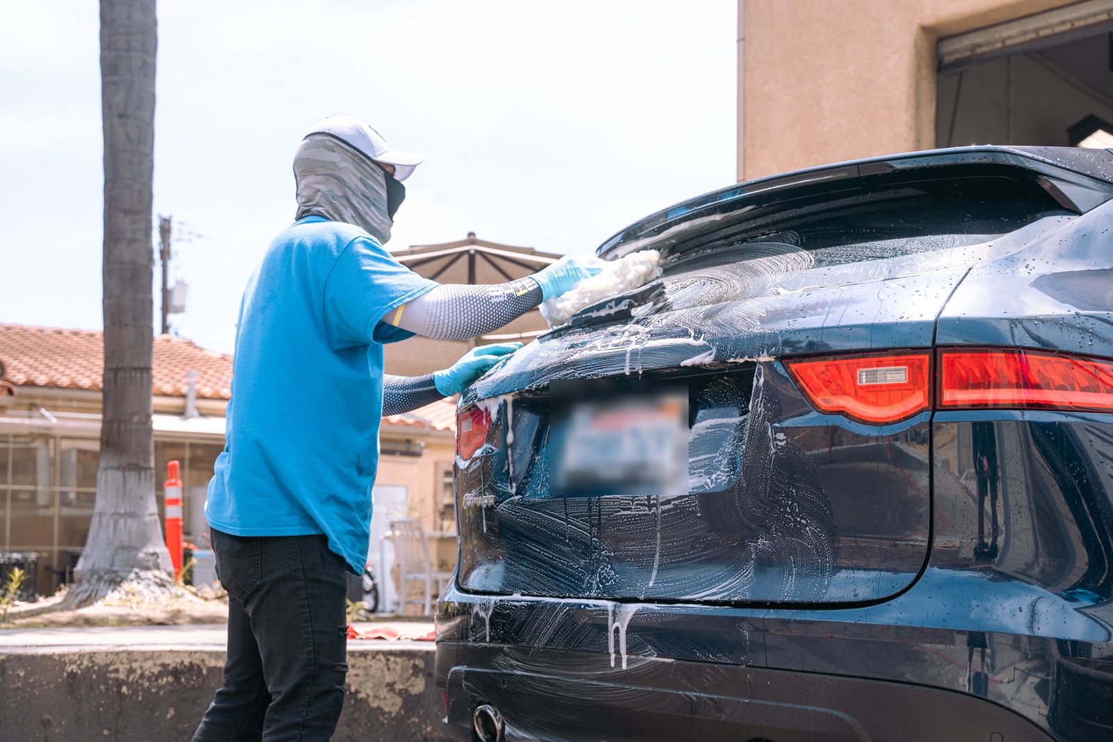 A crew member working suds across the rear glass of a navy Jaguar F-Pace