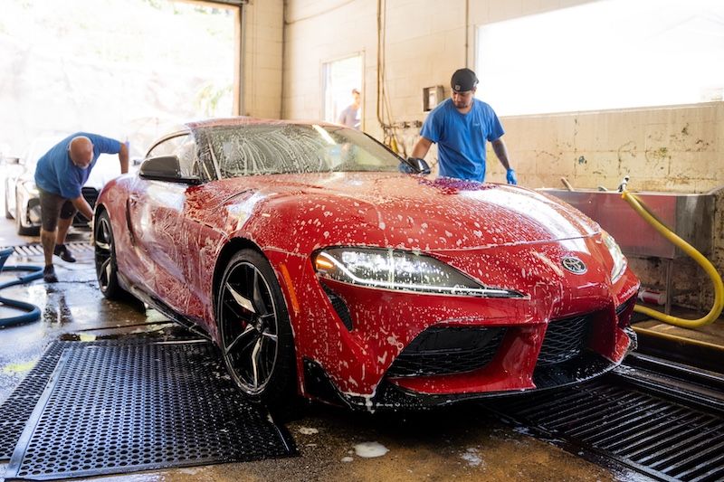 A soaped red Toyota Supra in the wash bay